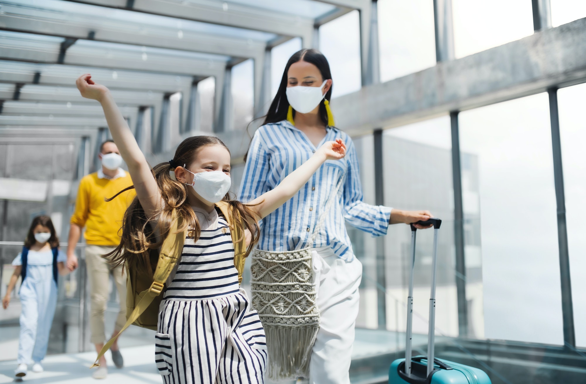 Family with two children going on holiday, wearing face masks at the airport
